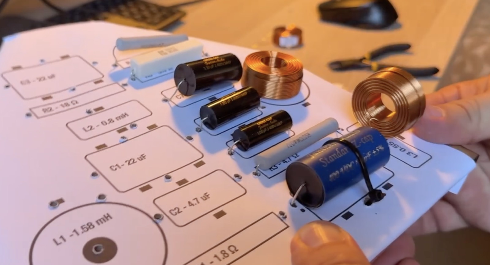 Los componentes sobre el esquema impreso del crossover: L1 1,58 mH, C1 22 µF, C2 4,7 µF…